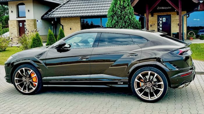 Czarne Lamborghini Urus zaparkowane przed zajazdem
