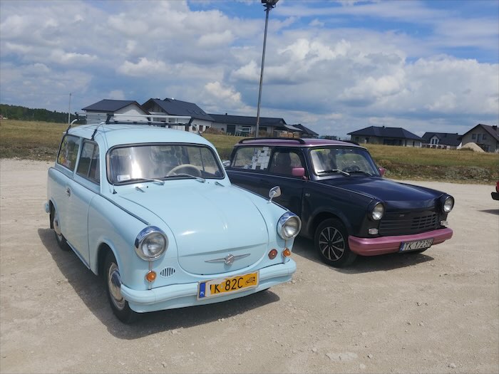 Dwa klasyczne Trabanty kombi, błękitny i fioletowy, na parkingu