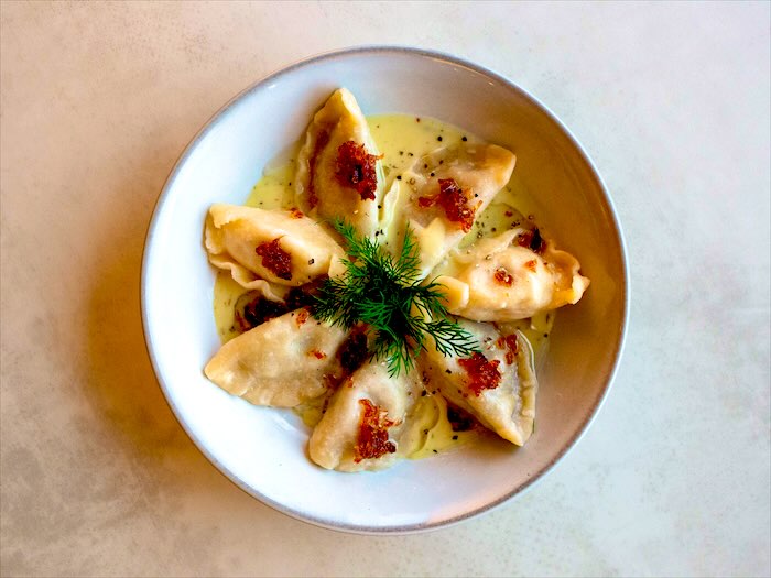 Pierogi w maślanym sosie ze skwarkami i gałązką koperku